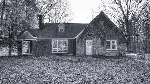 view of front of property with a shingled roof and brick siding