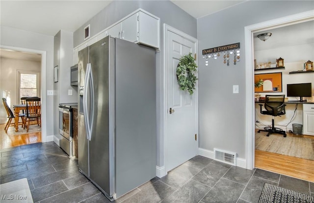 kitchen with baseboards, appliances with stainless steel finishes, visible vents, and white cabinetry