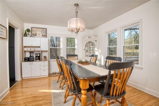 dining room featuring a chandelier, light wood-style flooring, and baseboards