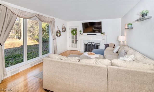 living area with light wood-style floors, visible vents, and a fireplace