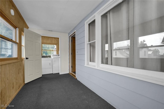 interior space featuring wood walls, washing machine and dryer, and dark colored carpet