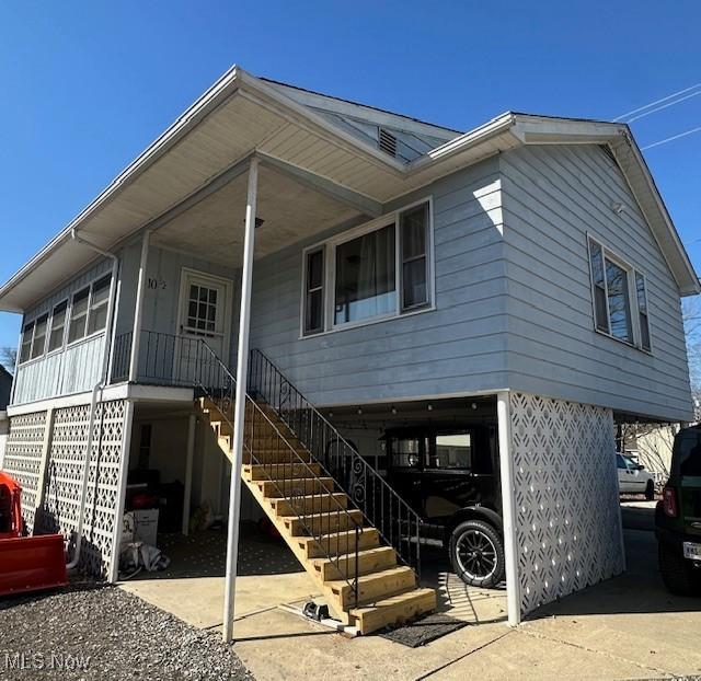 rear view of house with stairs, a carport, and a porch