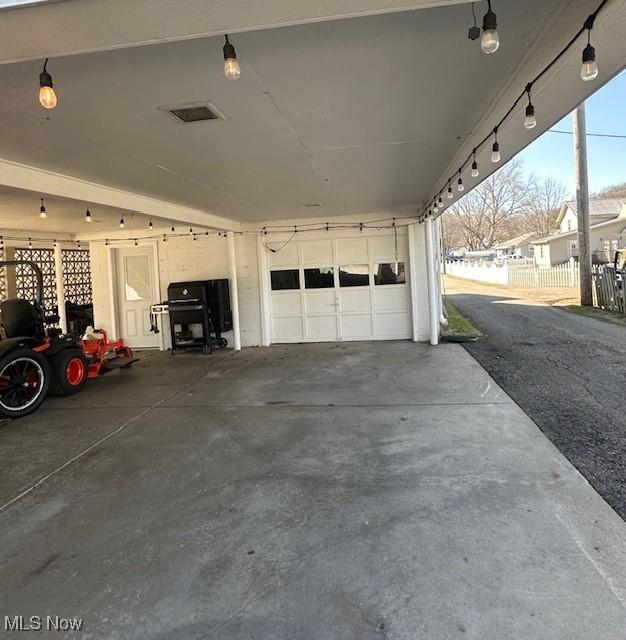 garage with a carport and fence