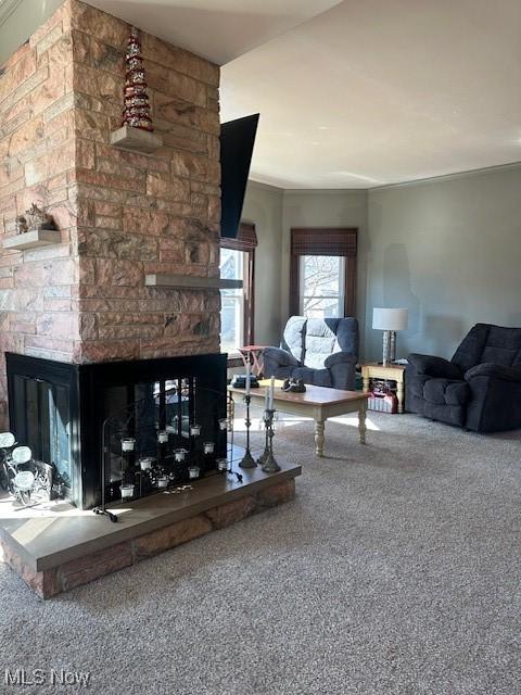 carpeted living area featuring a stone fireplace