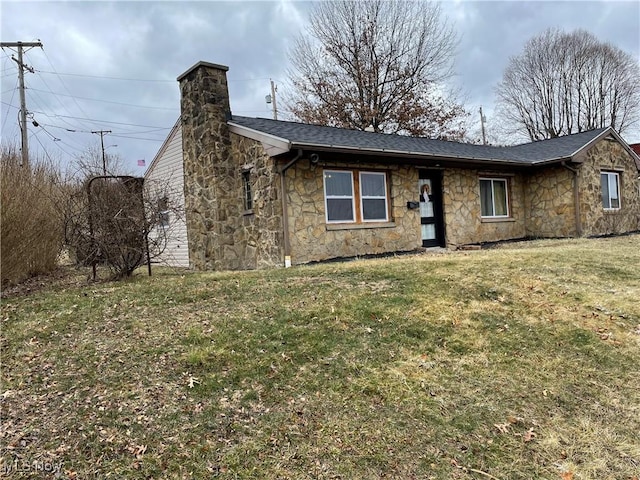 view of front of house featuring stone siding, roof with shingles, a chimney, and a front lawn