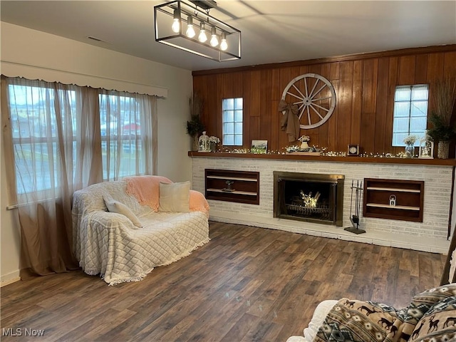 sitting room featuring a brick fireplace, wooden walls, and wood finished floors