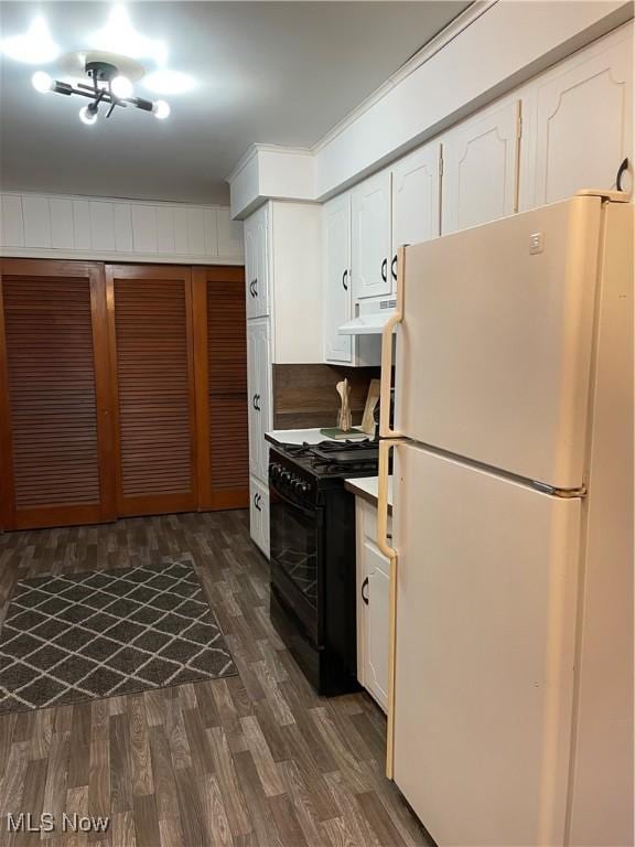 kitchen with black gas range, dark wood-style floors, freestanding refrigerator, extractor fan, and white cabinetry