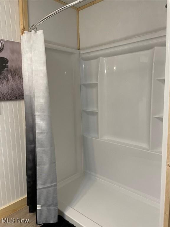 full bath featuring a shower with shower curtain and wood finished floors