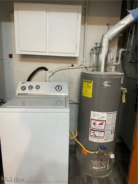 clothes washing area featuring washer / clothes dryer, gas water heater, and cabinet space