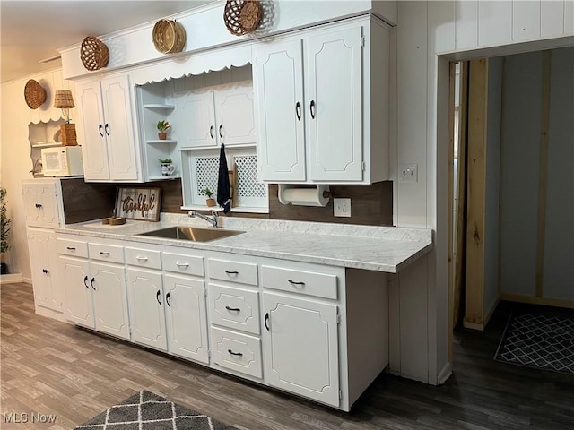 kitchen featuring dark wood-type flooring, light countertops, white cabinetry, open shelves, and a sink