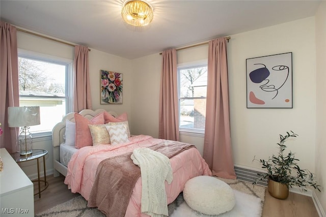 bedroom featuring multiple windows, wood finished floors, visible vents, and baseboards