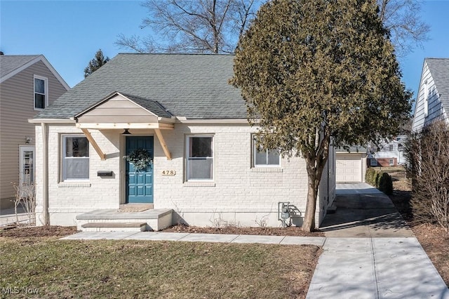 view of front of property with a garage, concrete driveway, brick siding, and a shingled roof