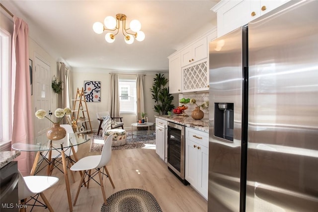 kitchen featuring beverage cooler, white cabinets, light stone counters, light wood-type flooring, and stainless steel refrigerator with ice dispenser