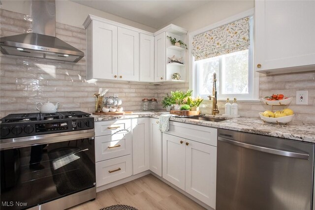 kitchen with stainless steel dishwasher, gas stove, a sink, wall chimney range hood, and light stone countertops