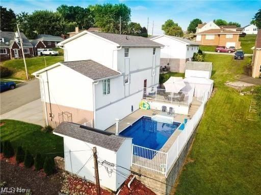 back of house with stucco siding, a residential view, and a yard