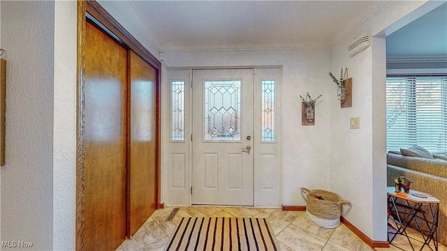 entryway with a textured wall, crown molding, and baseboards