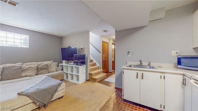 kitchen featuring light countertops, white cabinets, stainless steel microwave, and a sink