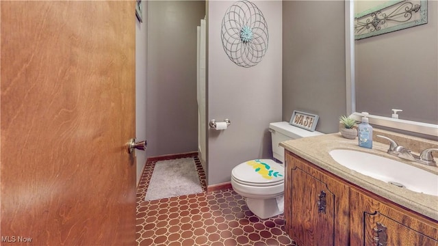 bathroom featuring toilet, baseboards, and vanity