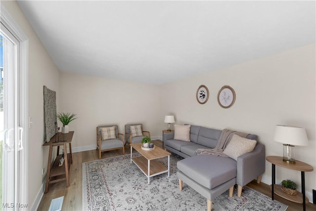 living area featuring wood finished floors, visible vents, and baseboards