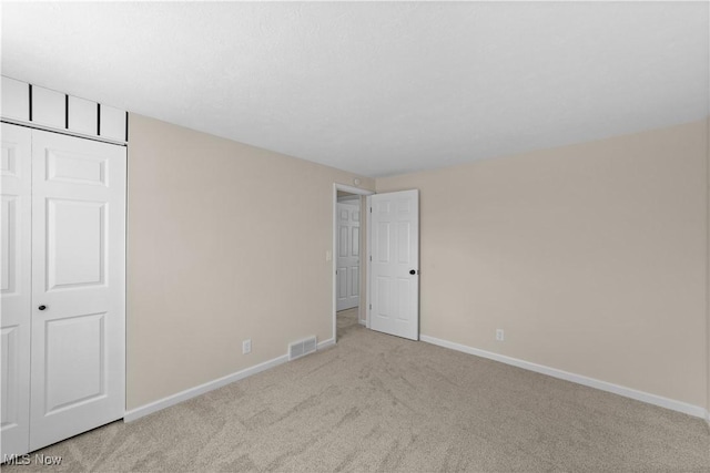 unfurnished bedroom featuring carpet floors, a closet, visible vents, and baseboards