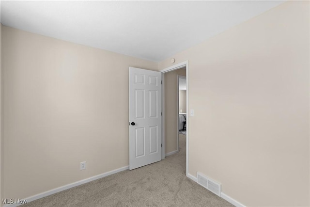 spare room featuring light carpet, baseboards, and visible vents