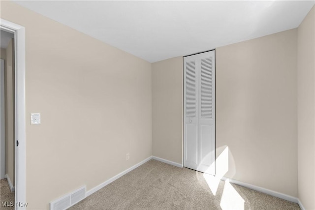 unfurnished bedroom with carpet floors, a closet, visible vents, and baseboards