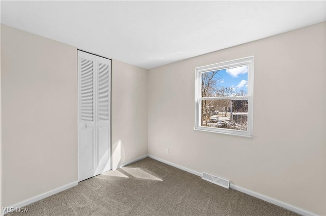 unfurnished bedroom featuring carpet floors, baseboards, visible vents, and a closet