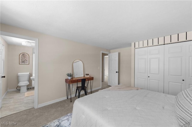 bedroom with a closet, light carpet, baseboards, and ensuite bathroom