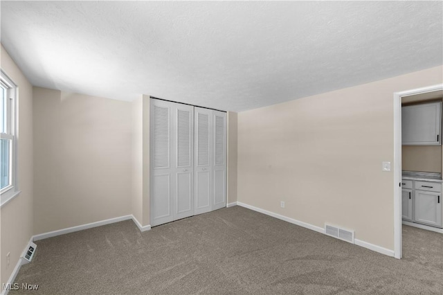 unfurnished bedroom with carpet floors, visible vents, and baseboards