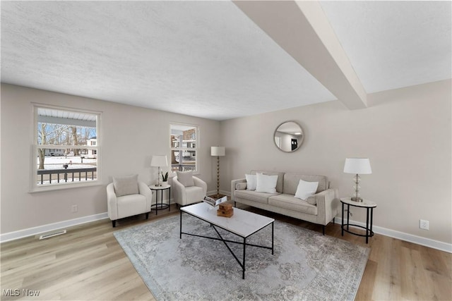 living area with visible vents, baseboards, and wood finished floors