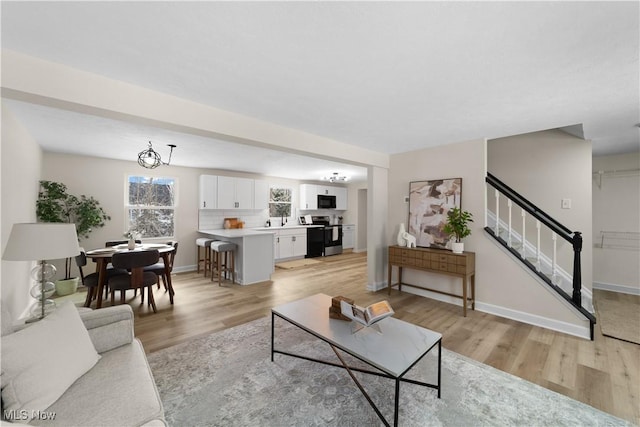 living area featuring light wood finished floors, stairway, and baseboards