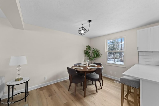 dining area with light wood-type flooring and baseboards