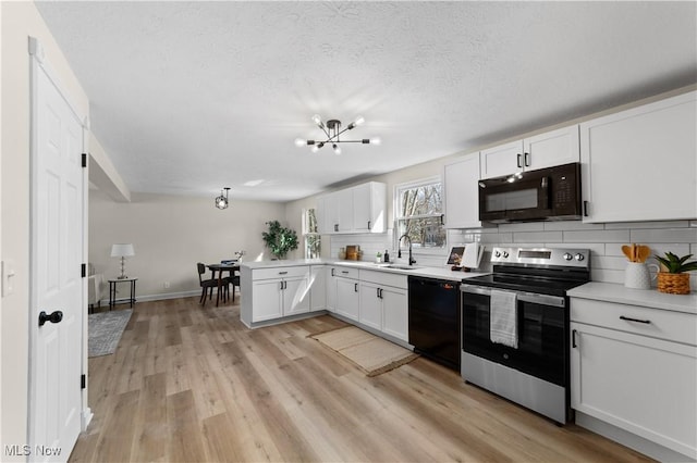 kitchen featuring light wood-style flooring, backsplash, white cabinetry, a sink, and black appliances