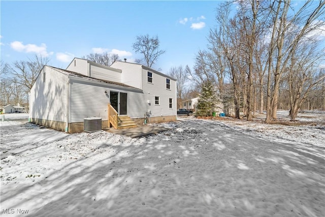 snow covered back of property featuring entry steps and cooling unit