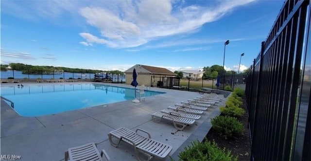 pool featuring an outbuilding, fence, and a patio