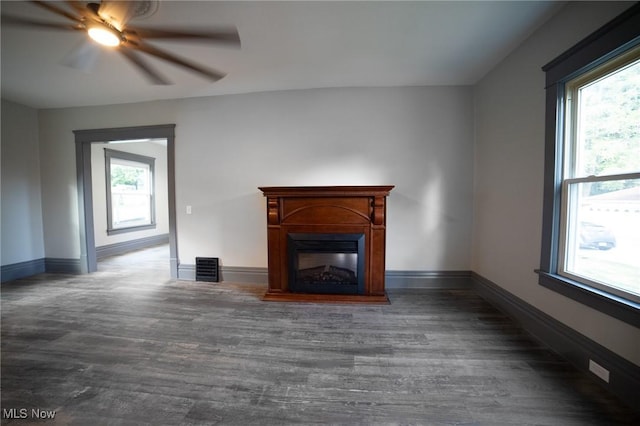 unfurnished living room with a glass covered fireplace, plenty of natural light, baseboards, and wood finished floors