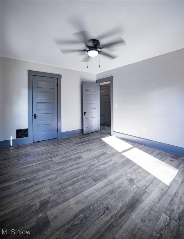 unfurnished bedroom featuring visible vents, a ceiling fan, baseboards, and wood finished floors