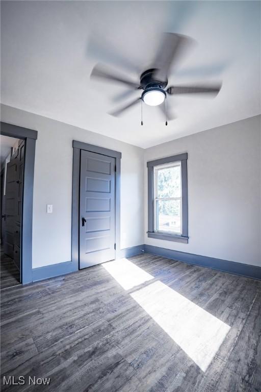 unfurnished bedroom featuring baseboards, wood finished floors, and a ceiling fan