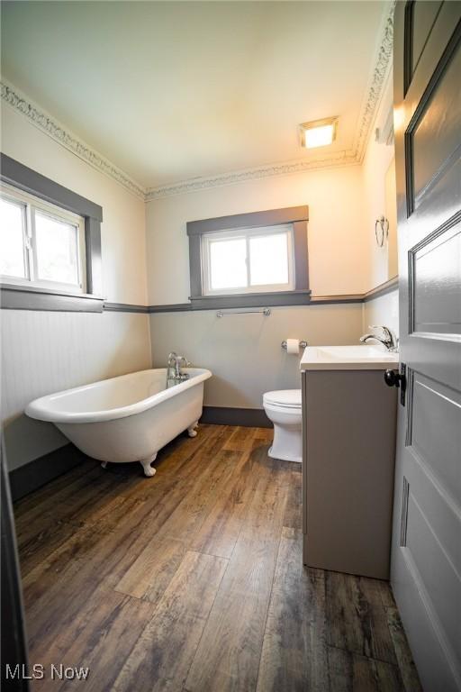 full bathroom featuring a freestanding bath, wood finished floors, vanity, and toilet