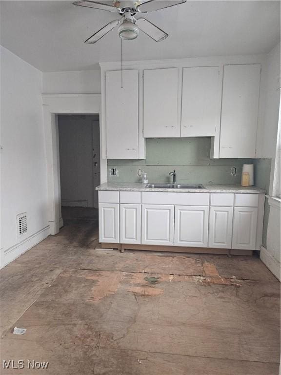 kitchen with a ceiling fan, a sink, decorative backsplash, light countertops, and white cabinets