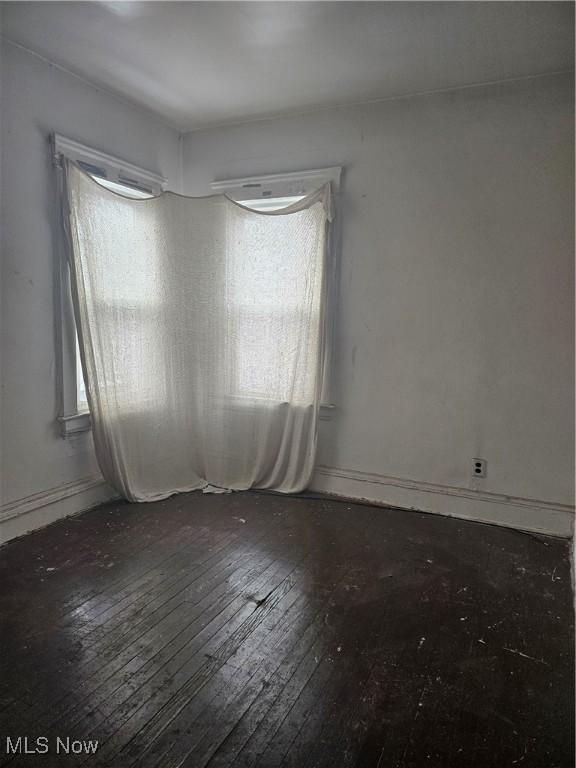 empty room with baseboards and wood-type flooring