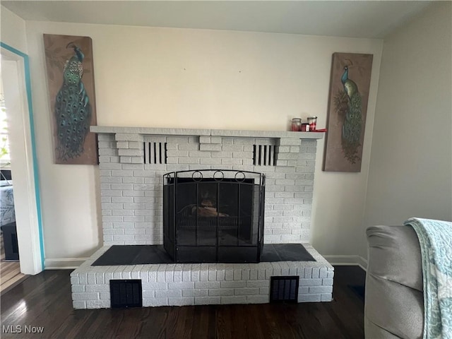 interior details with visible vents, a fireplace, baseboards, and wood finished floors