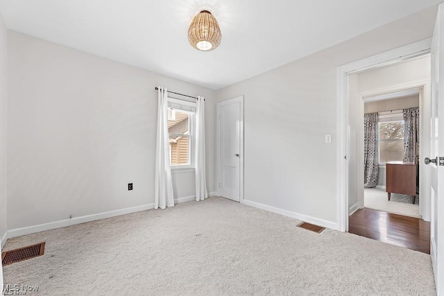 empty room with carpet floors, visible vents, and baseboards