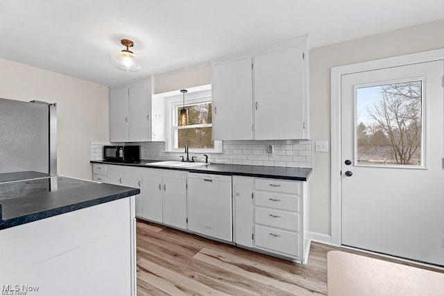 kitchen with black microwave, white dishwasher, dark countertops, and freestanding refrigerator