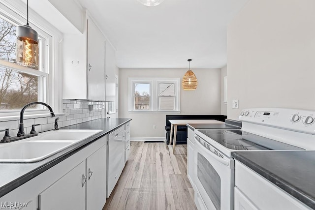 kitchen with tasteful backsplash, light wood-style flooring, white cabinetry, a sink, and white appliances