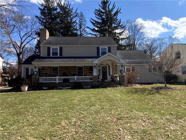 view of front of property featuring stone siding, a chimney, a front lawn, and covered porch