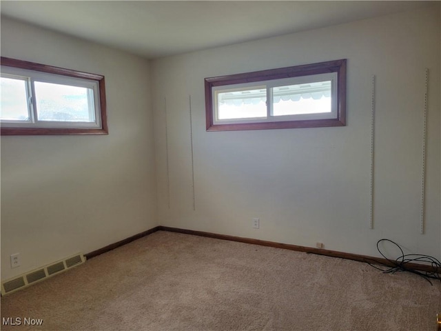 unfurnished room featuring visible vents, light carpet, and baseboards