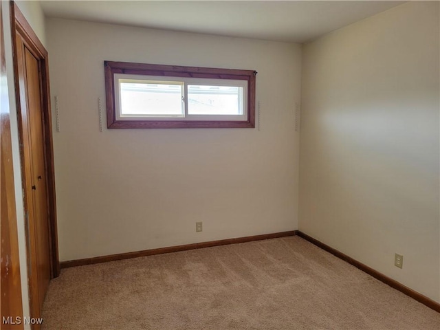 unfurnished room featuring light colored carpet and baseboards