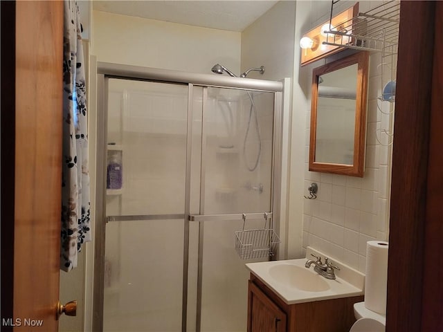 bathroom featuring a stall shower, tile walls, and vanity