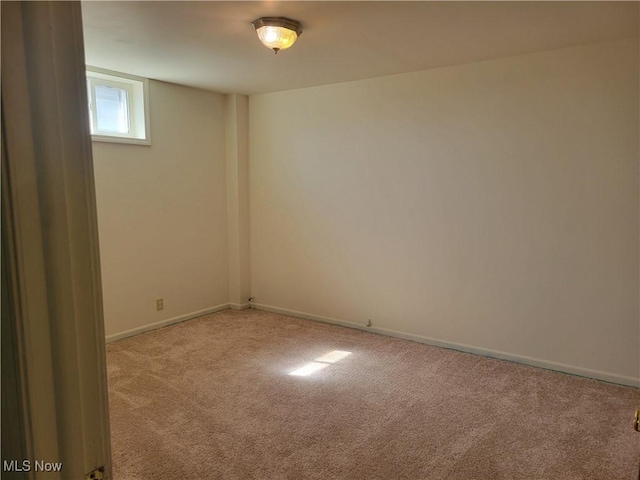 spare room featuring carpet floors and baseboards